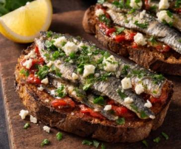 Pan-fried sardine toasts with garlic, chilli, and lemon zest on a rustic wooden board